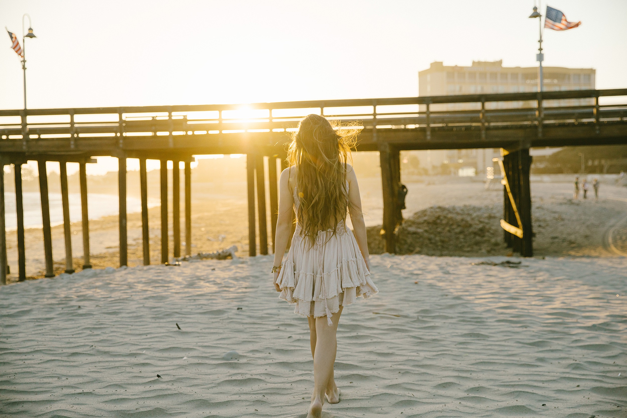 Backlit portrait of a senior girl walking on the beach at sunset at Ventura pier