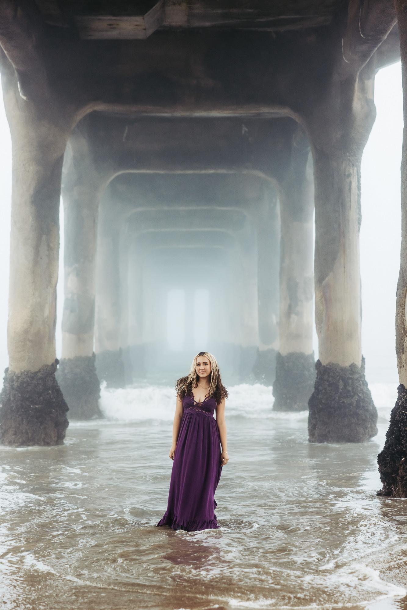 Editorial senior pictures of a Saugus High senior wearing a purple dress in the ocean at Manhattan Beach.