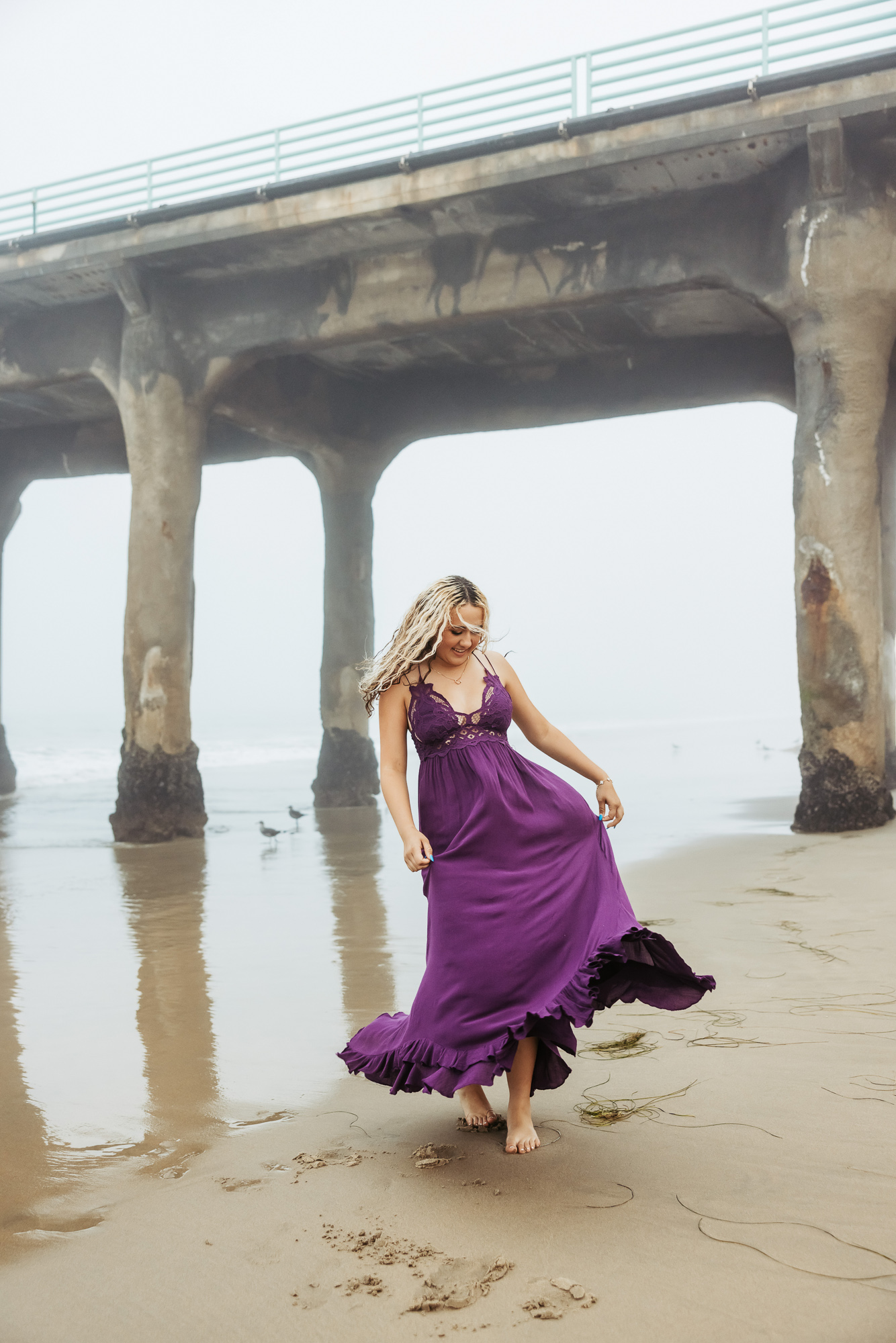 Action shot of a high school senior walking along the shoreline for Manhattan Beach senior photos.
