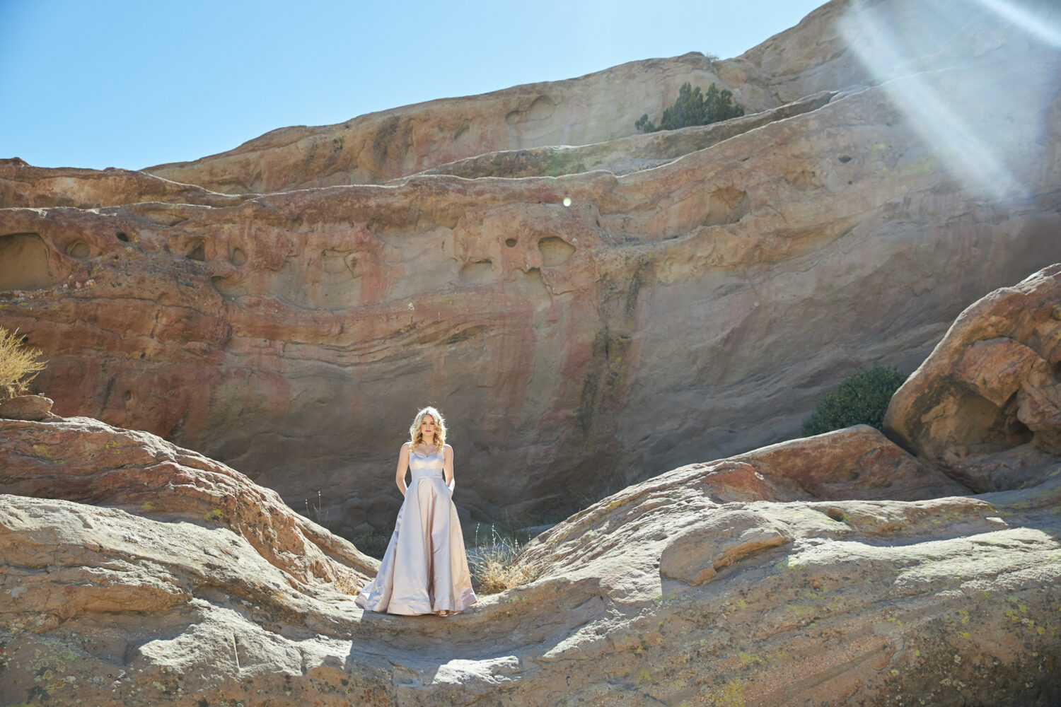Senior girl in a blush satin ball gown standing on the sandstone at Vasquez Rocks near Santa Clarita