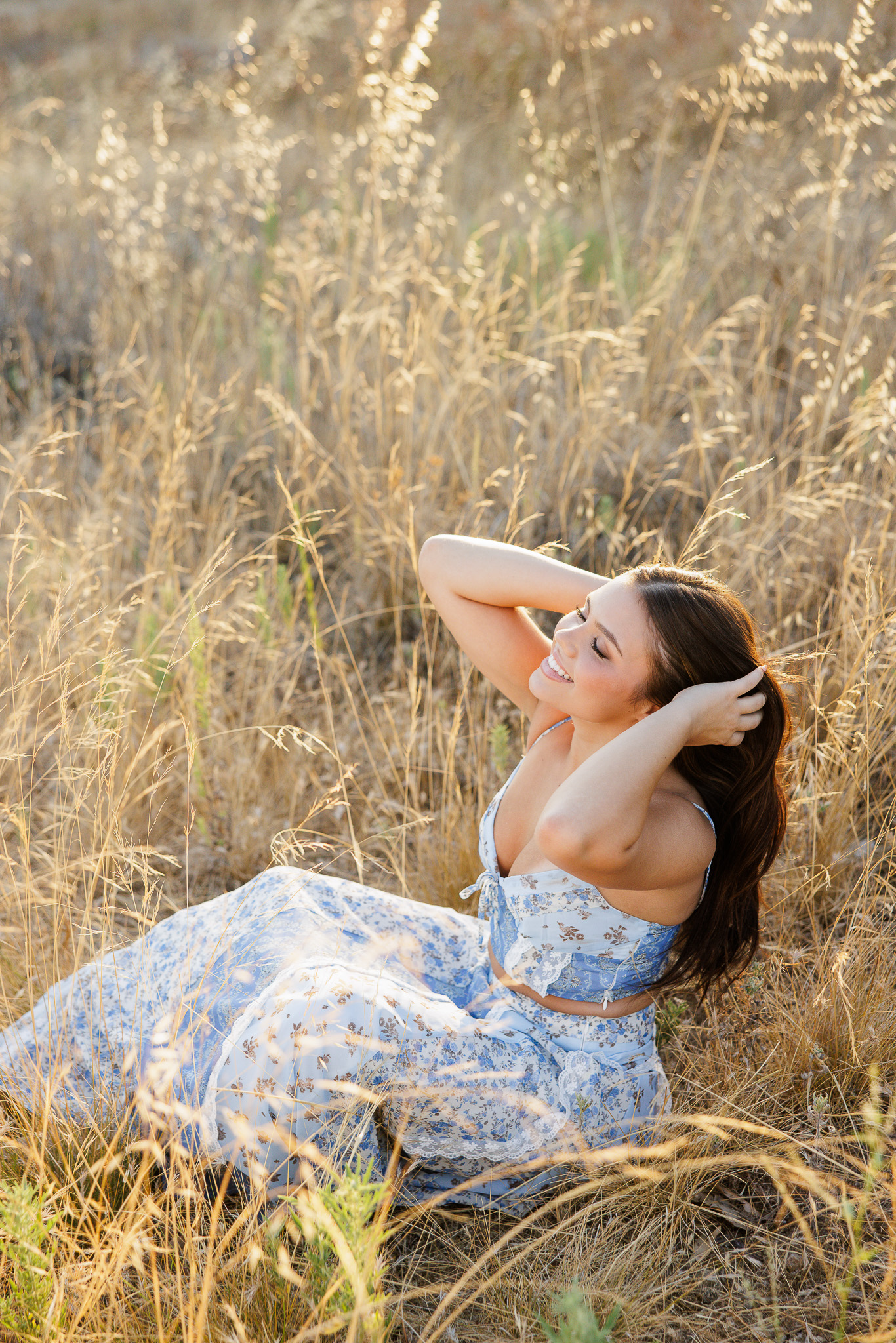 teen girl the blue floral set surrounded by tall golden grass and hillside at golden hour sunset in Santa Clarita