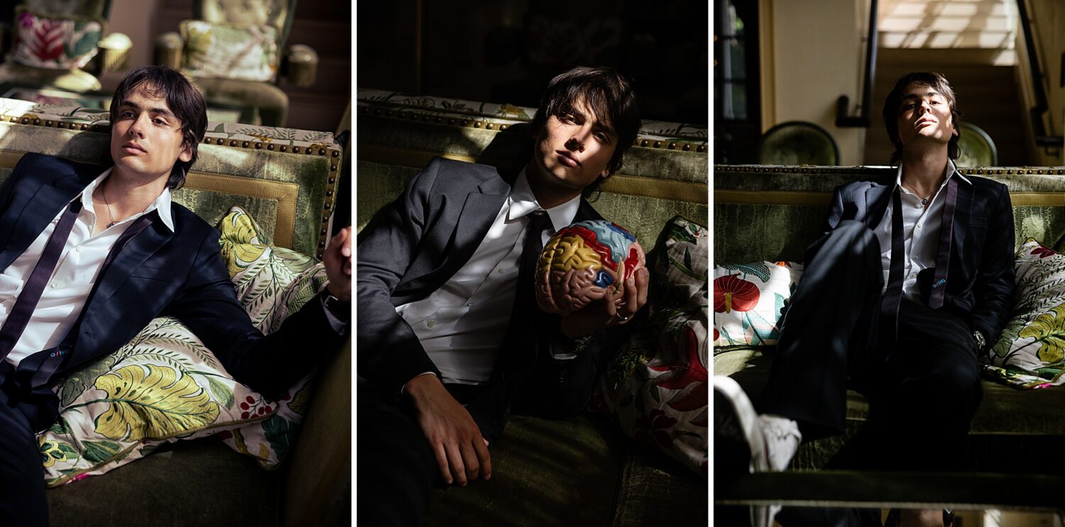 Southern California guys senior pictures of a senior guy in a navy suit reclining on a green velvet couch with a colorful brain model