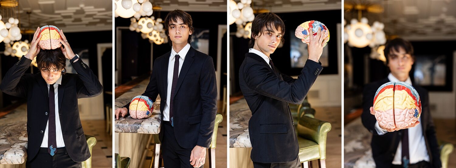 Southern California guys senior pictures of a senior guy in a black suit posing with a neuroscience brain model at a marble bar